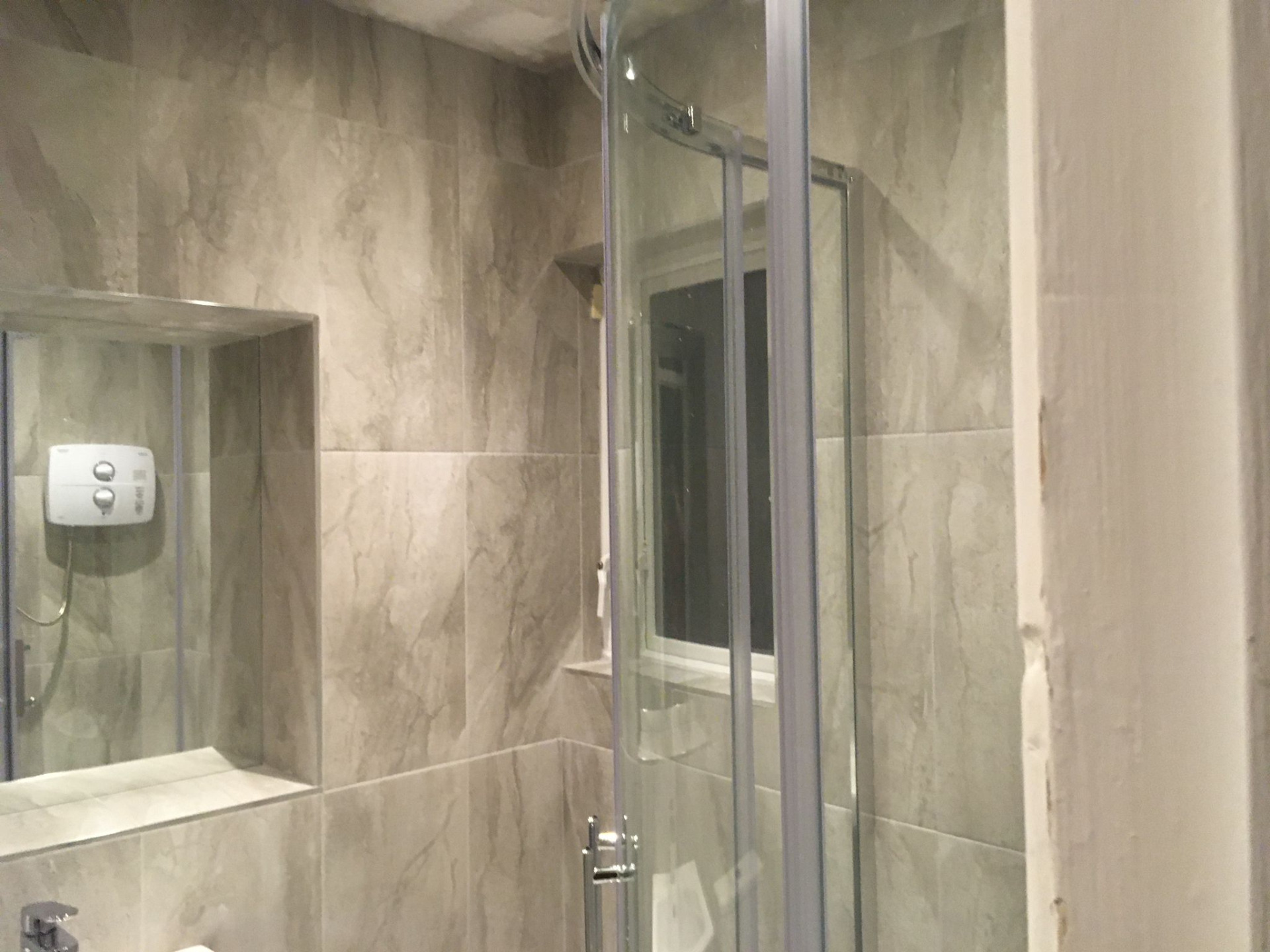 Floor to ceiling tiling with recessed shelf and mirror installed by Elite Building Services Swords